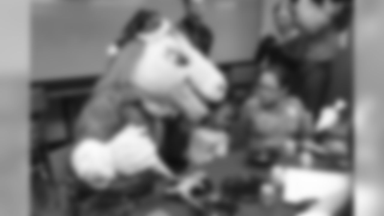 Miles the mascot kisses a young girl decorates gingerbread cookies at the Denver Rescue Mission's 19th annual holiday party.
