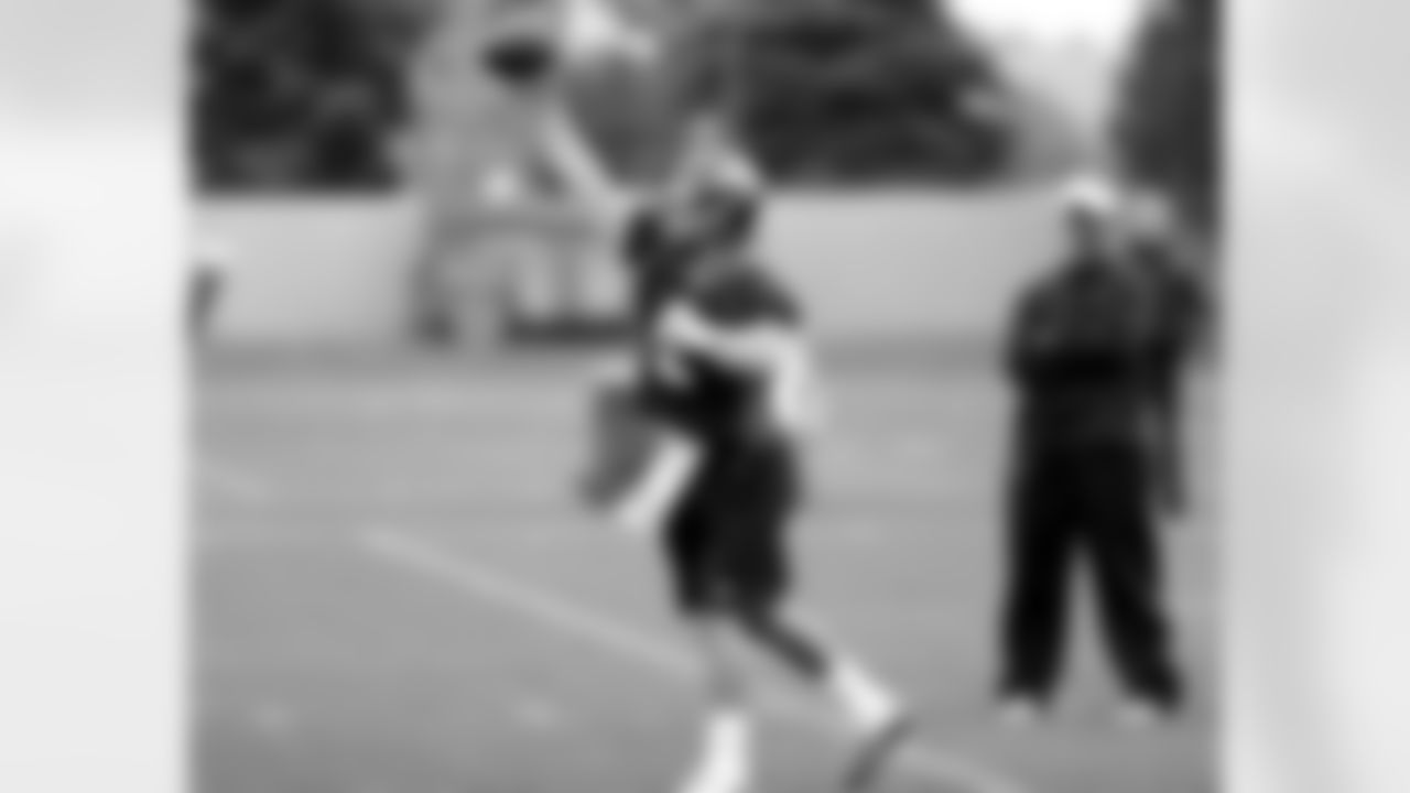QB Adam Weber throws a pass as offensive coordinator Mike McCoy watches.