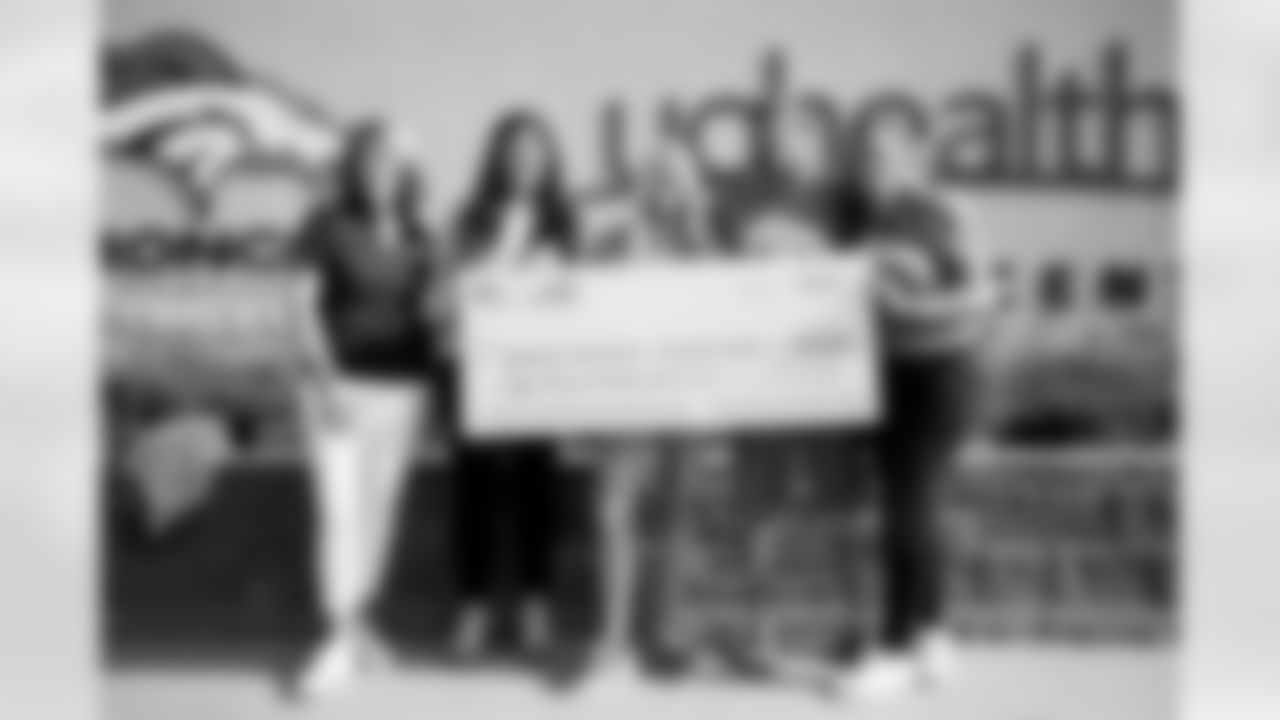 Nancy Thompson, Senior Director of Development for the Alzheimer's Association's Colorado chapter; Angie Ruddell, Empower Retirement Engagement & Corporate Social Responsibility Manager; Annabel Bowlen; Patrick Bowlen Jr.; and Senior Vice President of Strategy Brittany Bowlen pose for a photo with a $50,000 donation to the Alzheimer's Association's Colorado chapter during Alzheimer's Awareness Day at training camp at UCHealth Training Center on August 17, 2021. (Photo by Ben Swanson)
