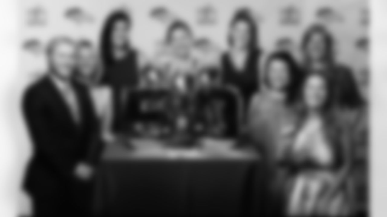 Kelsey Zimmerman, Executive Assistant to Chief Commercial Officer, poses for a photo with several of her colleagues and the team's Super Bowl trophies.