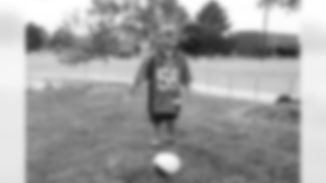 A young Broncos fan plays with a football at the Back Together Saturday event celebrating the return of fans to training camp at UCHealth Training Center on July 31, 2021. (Photo by Ben Swanson)