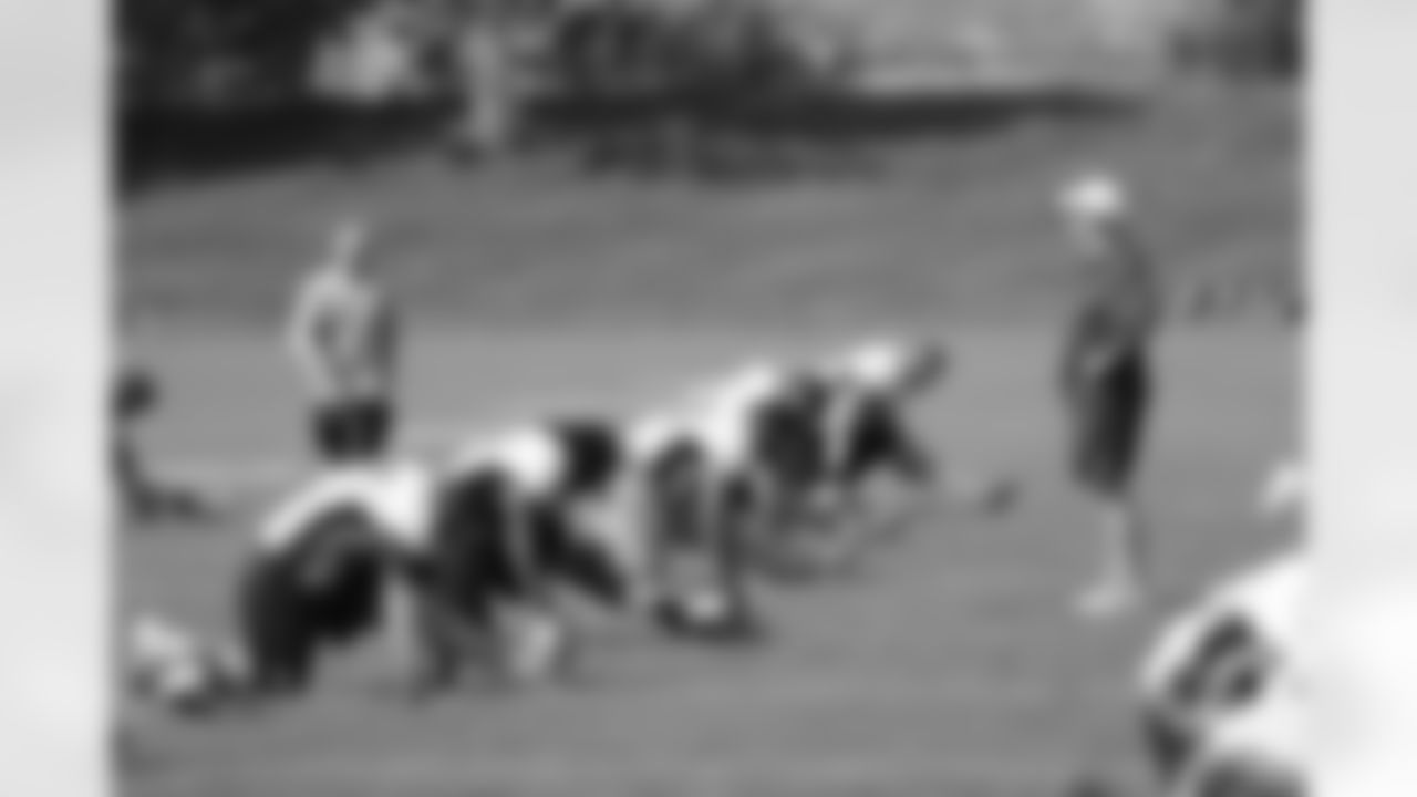 Head Coach John Fox talks to the defensive linemen while they stretch.