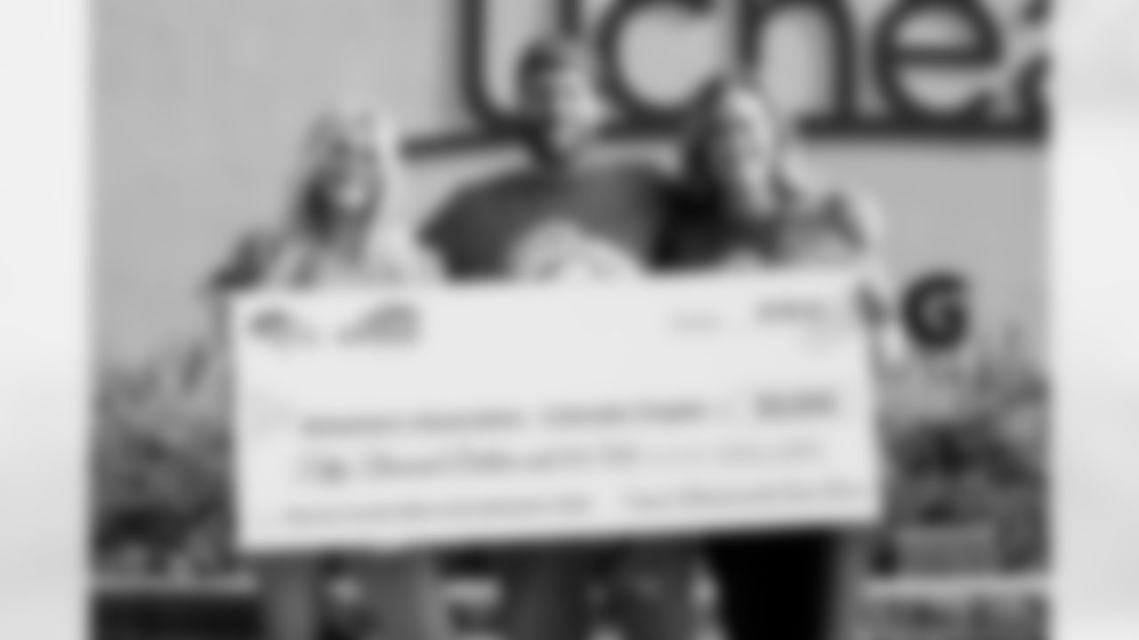 Annabel Bowlen, Patrick Bowlen Jr. and Senior Vice President of Strategy Brittany Bowlen pose for a photo with a $50,000 donation to the Alzheimer's Association's Colorado chapter during Alzheimer's Awareness Day at training camp at UCHealth Training Center on August 17, 2021. (Photo by Ben Swanson)