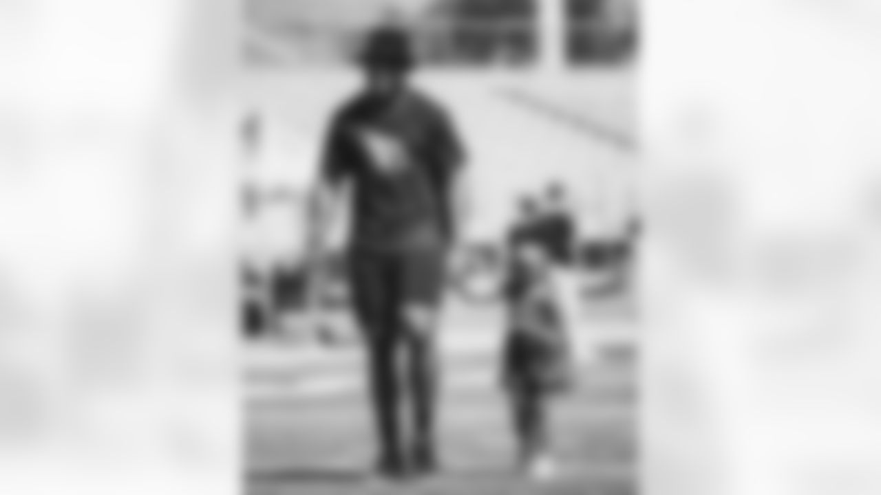 LB Devon Kennard walks across the field with a young girl.
