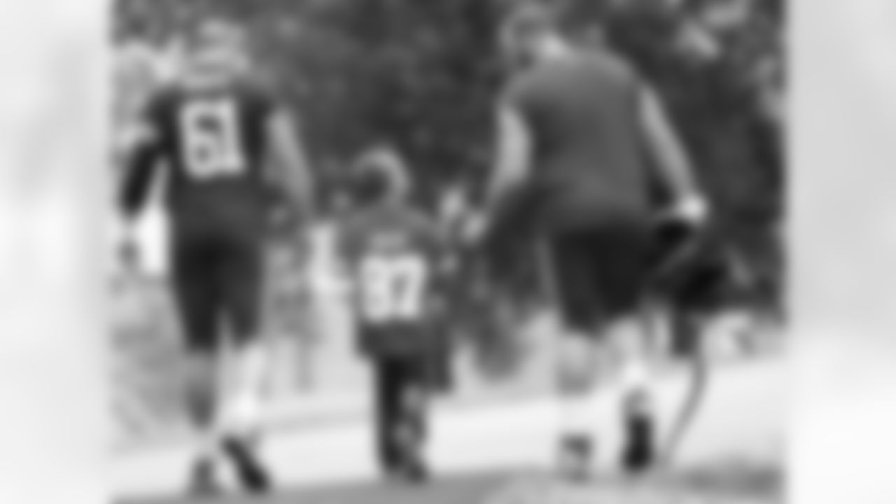 Kansas City Chiefs offensive lineman Mitch Morse (61) and Kansas City Chiefs offensive tackle Mitchell Schwartz (71) walk with a young fan during the helmet walk after practice 7/29/18 at Chiefs Training Camp at Missouri Western State University in St Joseph, Missouri