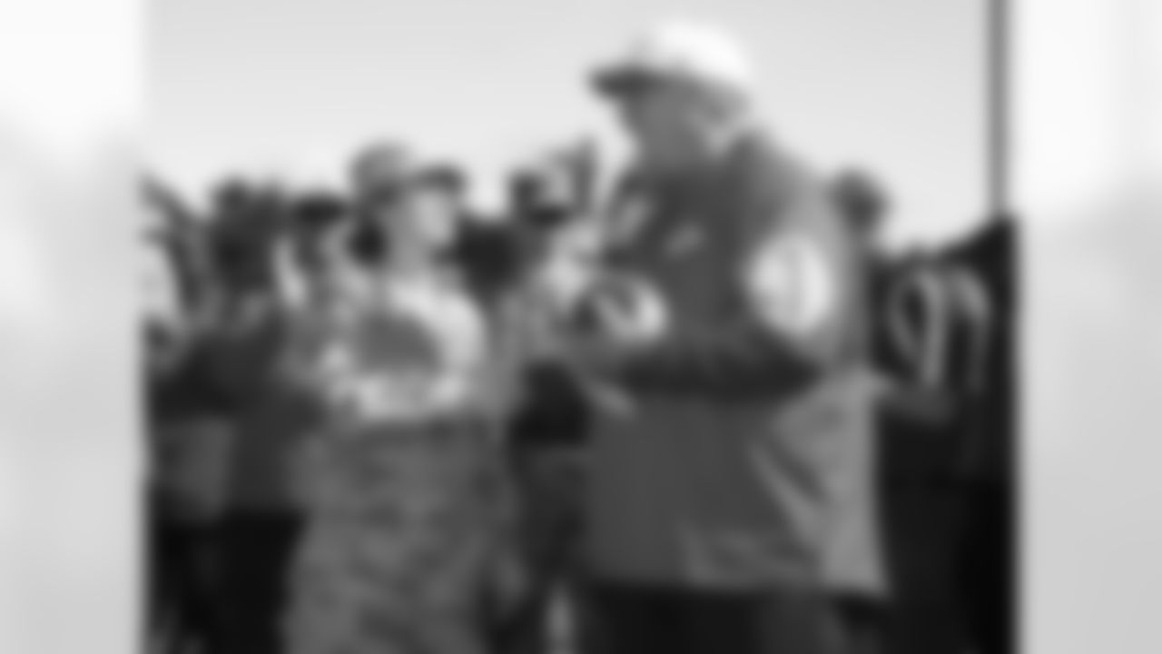 Head coach Andy Reid presents game ball to service woman on Military Appreciation Day at training camp.