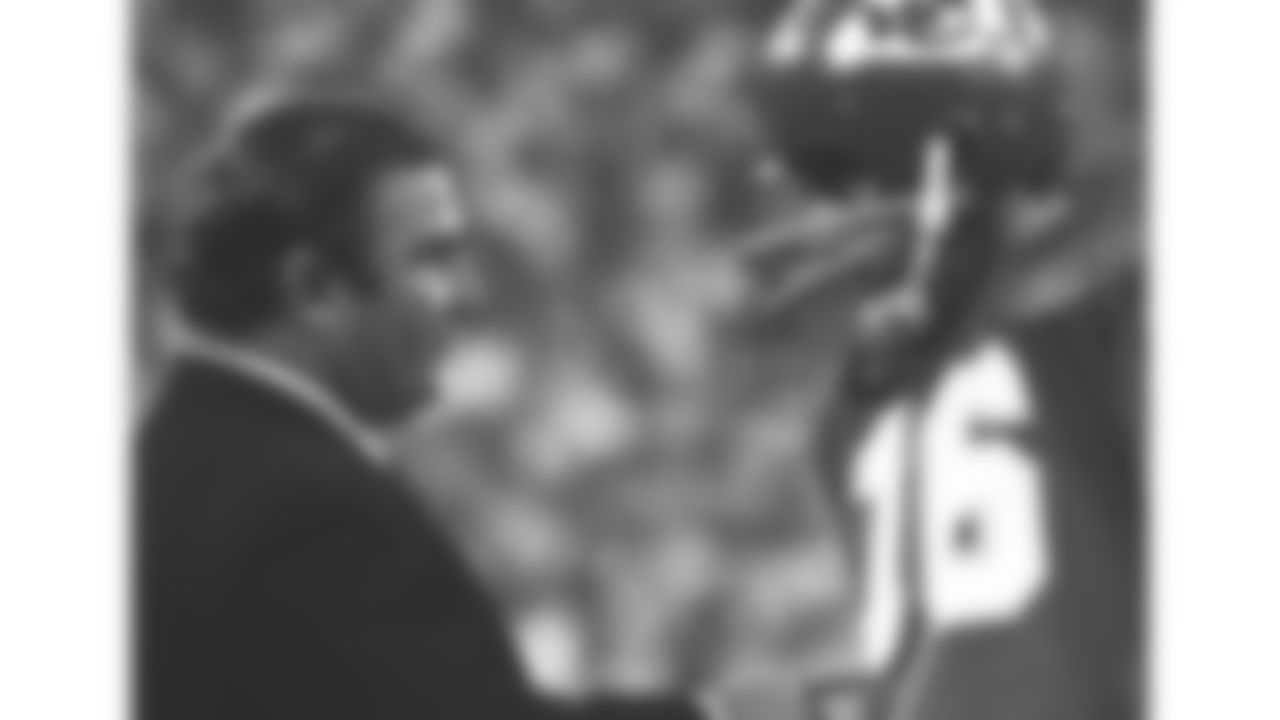 Hank Stram points to Len Dawson on the sidelines during a game as they talk.