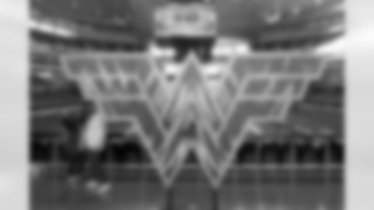 A pair of fans take a photo as they stand by a sculpture in the shape of the "Wonder Woman" logo on the main concourse of AT&T Stadium before an NFL football game between the San Francisco 49ers and Dallas Cowboys in Arlington, Texas, Sunday, Dec. 20, 2020. (AP Photo/Michael Ainsworth)