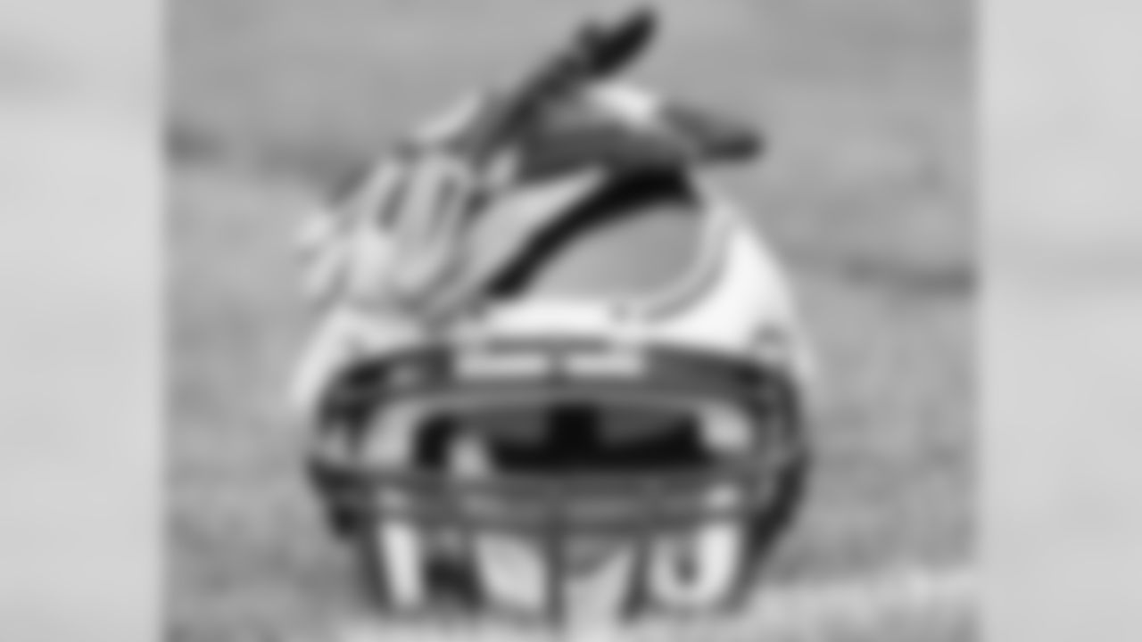 A pair of gloves on top of an Eagles helmet on the practice field