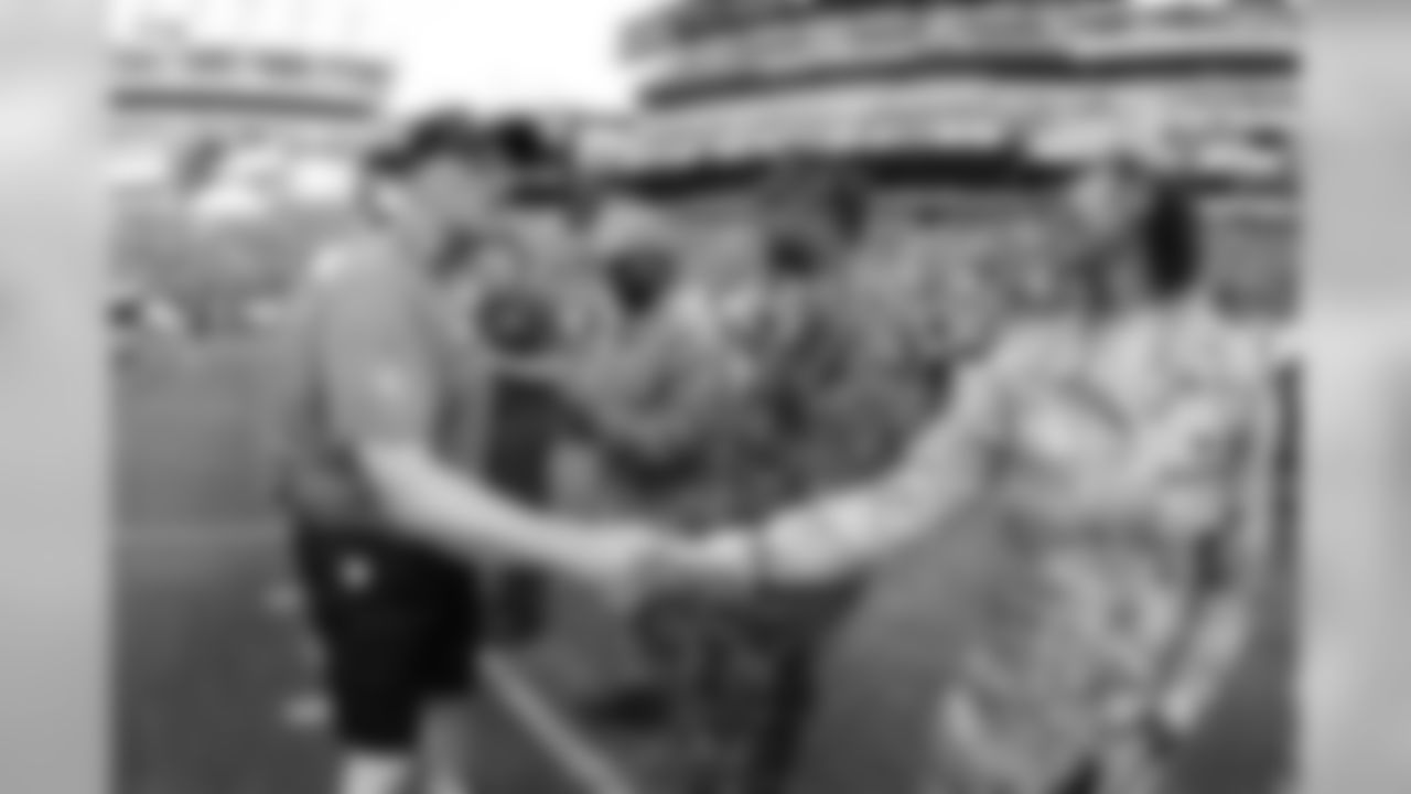 Linebackers coach Ken Flajole shakes hands with military members
