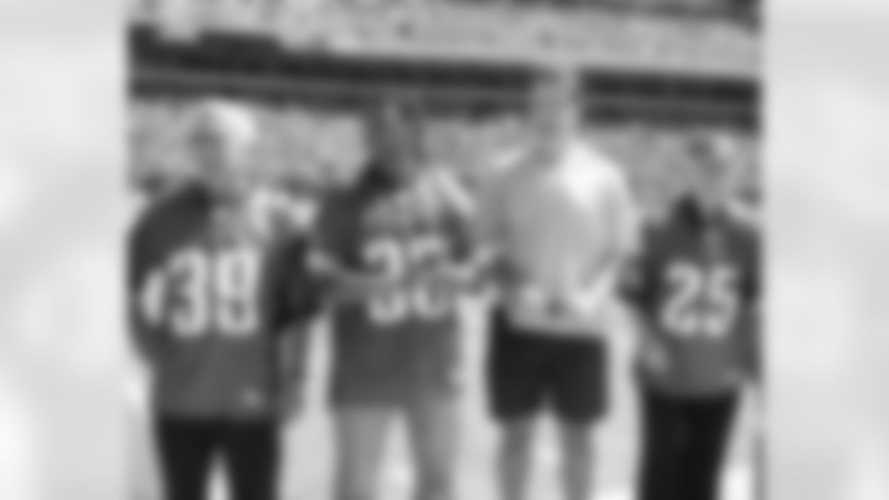 Some of the alumni look on, including Tommy McDonald (25) and Mike Mamula (tan shirt)