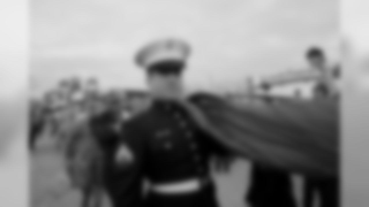 Military members carrying the American Flag into the game
