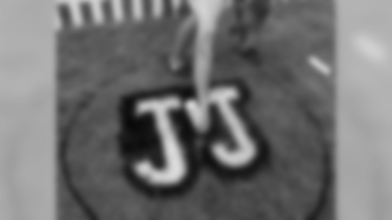 Michael Kontor, an intern with the Eagles, paints the letters JJ on the grass near the entrance to the team's training camp at Lehigh University