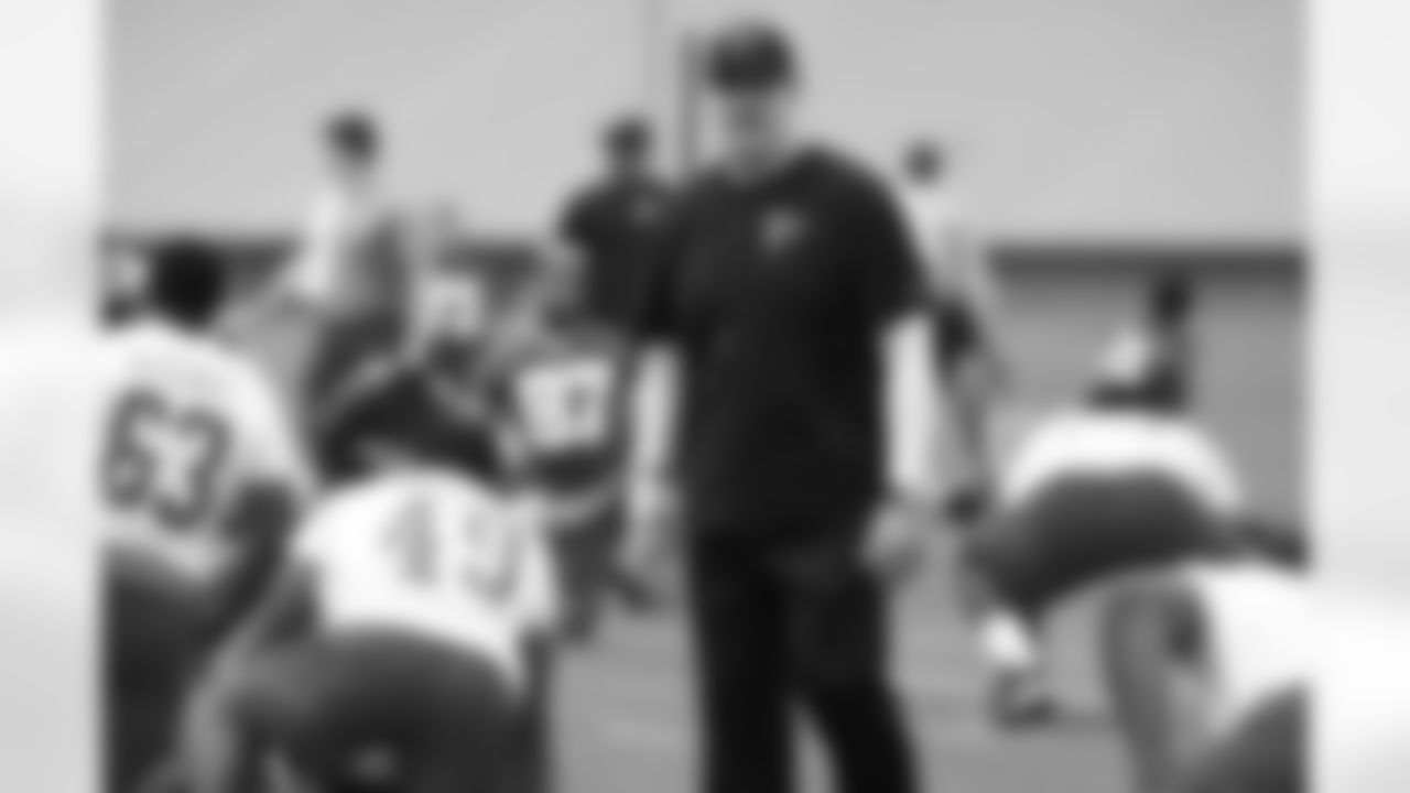 Dan Quinn, head coach, talks to players while they stretch