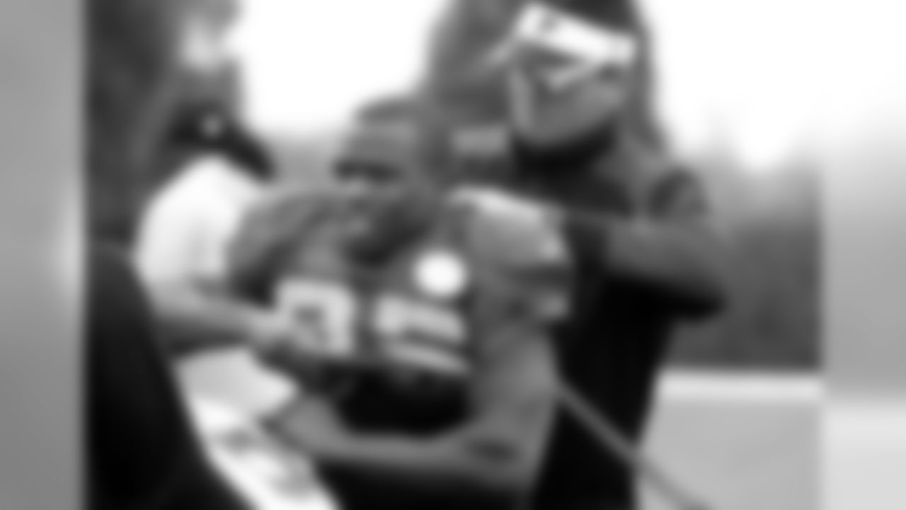AJ Neibel, head strength and conditioning coach, helps RB Antone Smith suit up for practice