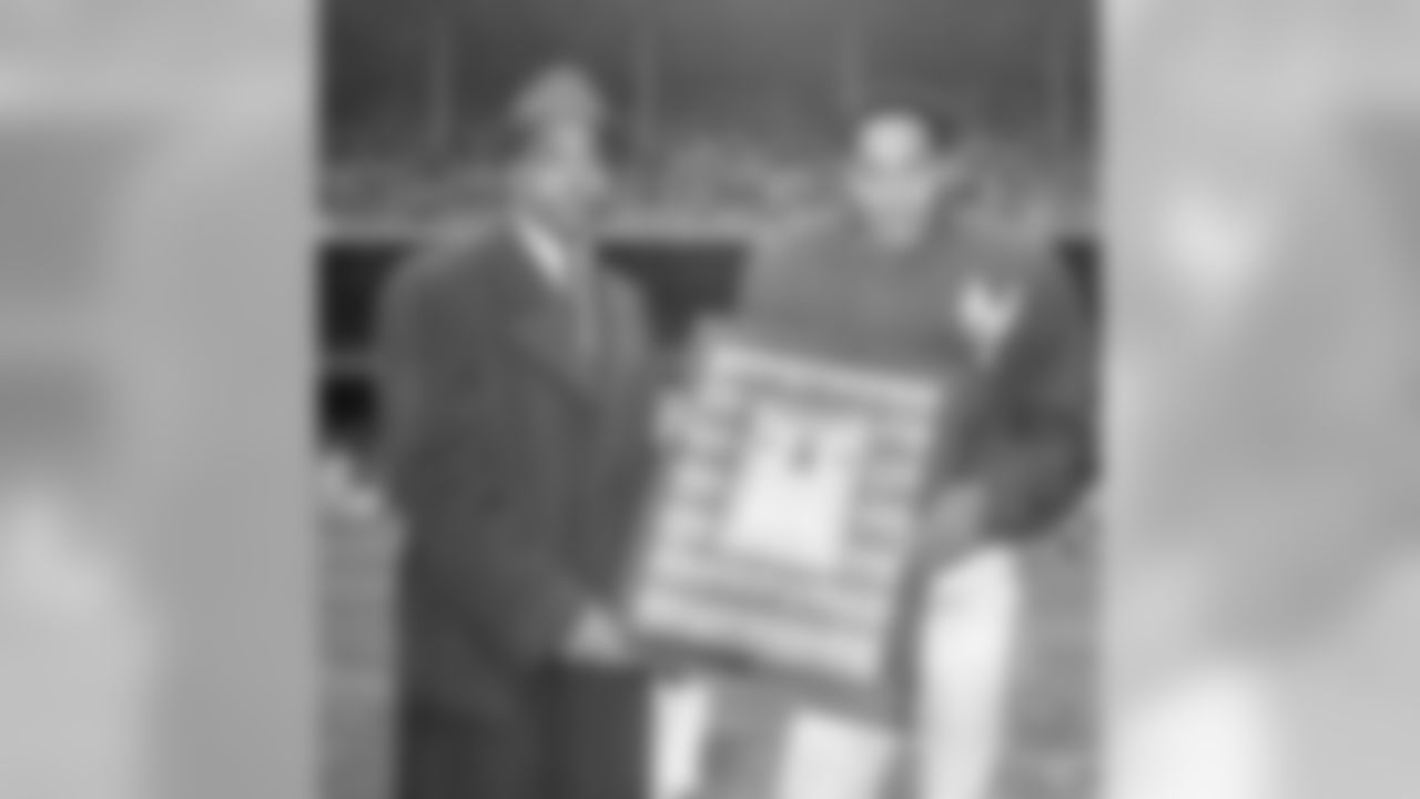 Emlen Tunnell, defensive halfback of the New York Giants football club, holds gift presented to him by former baseball Giants star Monte Irvin, before the game at Yankee Stadium in New York, Dec. 14, 1958. It was "Emlen Tunnell Day" at the stadium and among other gifts Tunnell received a testimonial surrounded by photos of teammates on the football Giants. Tunnell formerly played for Iowa University. (AP Photo/John Lindsay)