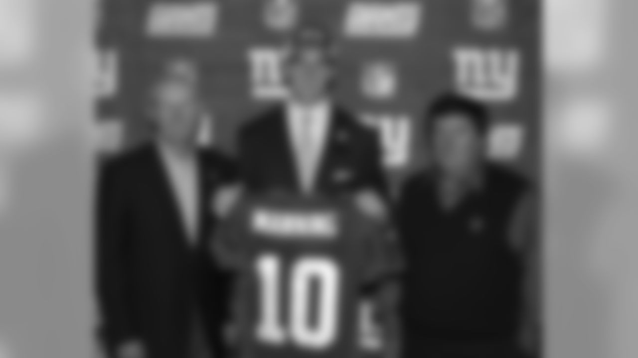 This April 24, 2004, file photo shows New York Giants draft pick Eli Manning holding up his new Giants jersey as he poses with coach Tom Coughlin, left, and general manager Ernie Accorsi in East Rutherford, N.J. (AP Photo/Bill Kostroun, File)