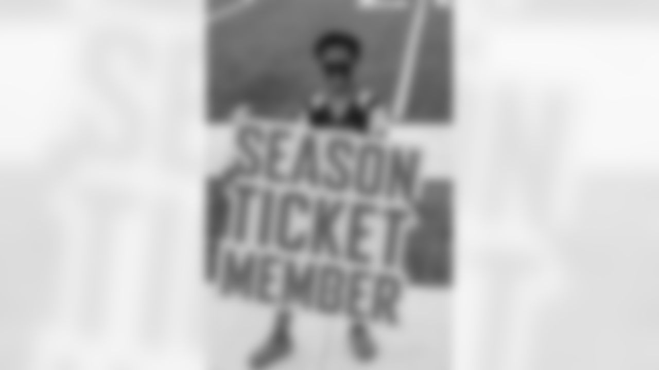 A founding season ticket member poses with a "Season Ticket member" sign.