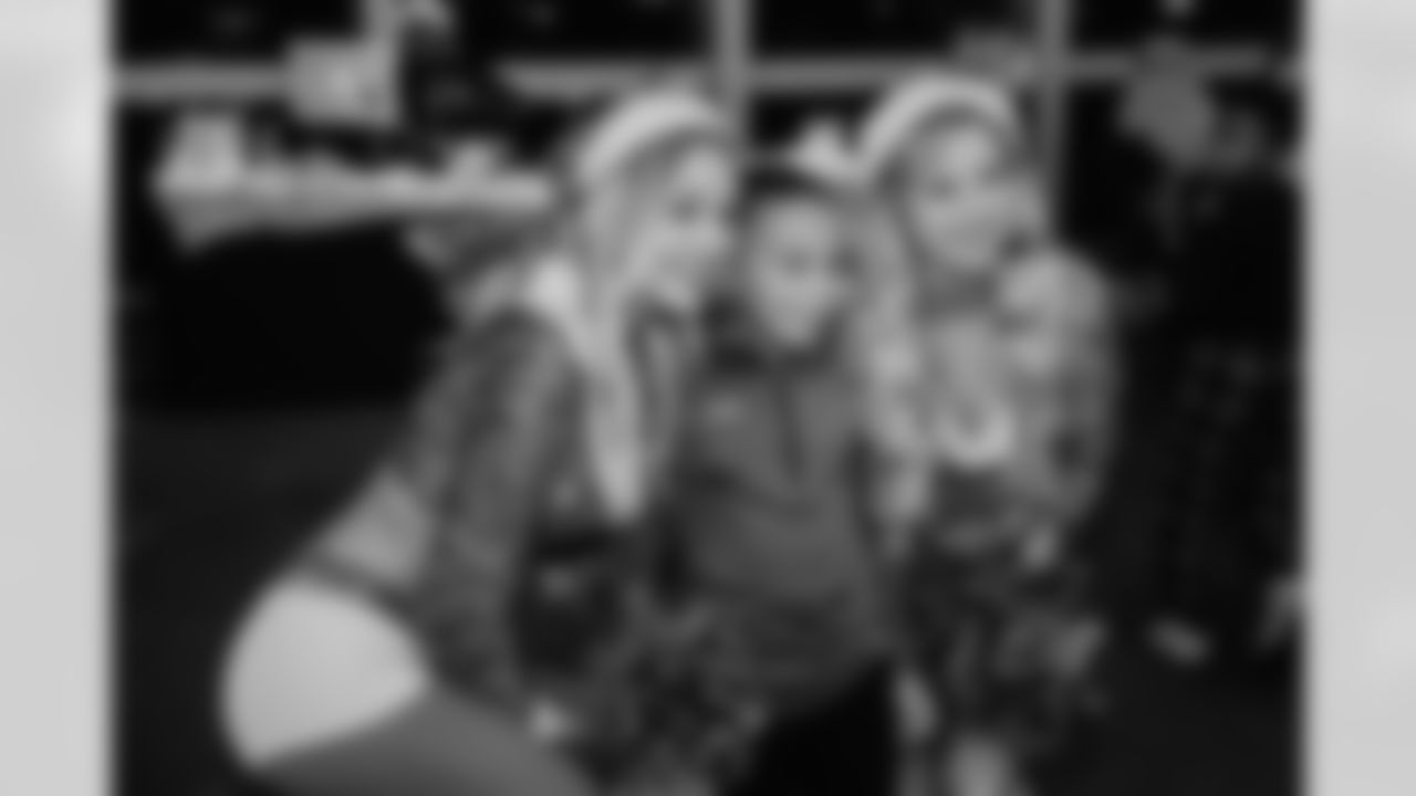 A Jaguars fan poses with two cheerleaders at the season ticket member holiday party.