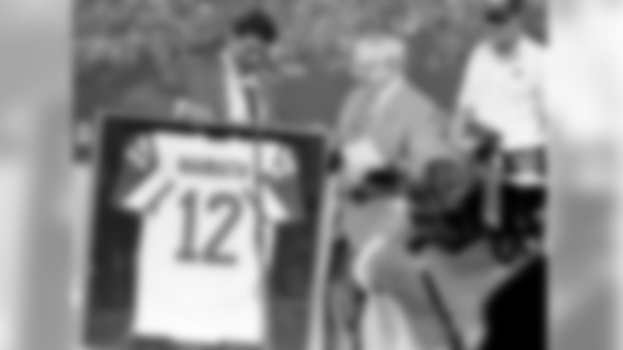 Former New York Jets quarterback Joe Namath looks down at his framed jersey, presented to him by his coach Weeb Ewbank, in East Rutherford, N.J., on October 15, 1985. The Jets retired Hall of Famer Namath's number in a halftime ceremony during the game between the Jets and the Miami Dolphins. (AP Photo/Ron Frehm)