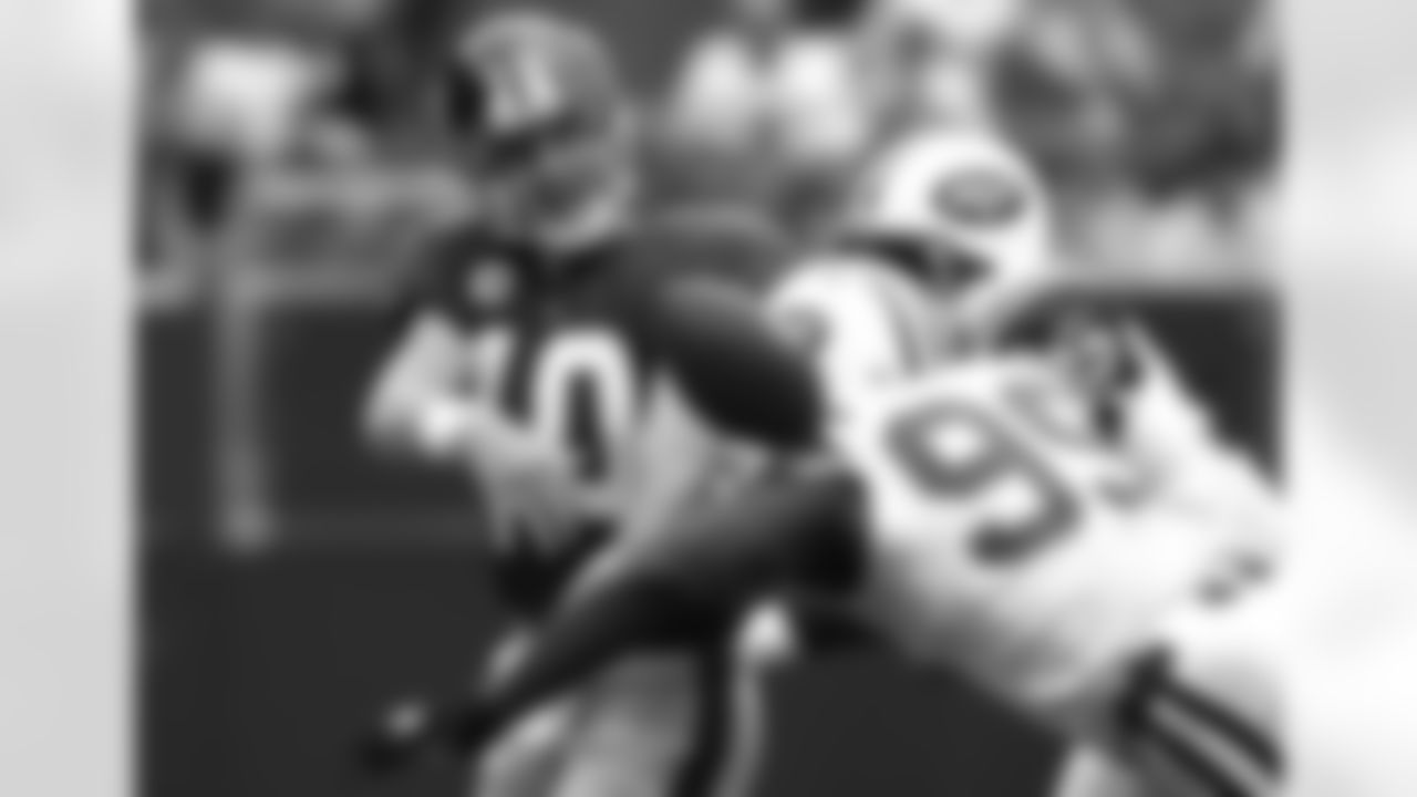 Eli Manning (10) scrambles under pressure from Bryan Thomas (99) and Shaun Ellis (92).