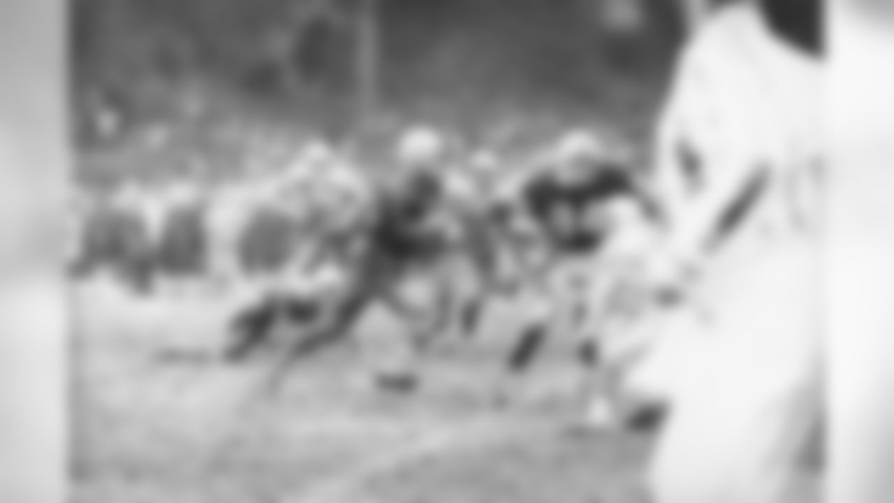 Mud-covered Paul Hornung, on a one-day pass from military duty, is shown reeling off yardage in third period action for the Green Bay Packers who virtually clinched another divisional title by beating the Detroit Lions 17-9, Nov. 24, 1961, in Detroit. Teammate Gary Knafelc (84) moves in to take out Gary Lowe (43) of the Lions. (AP Photo)