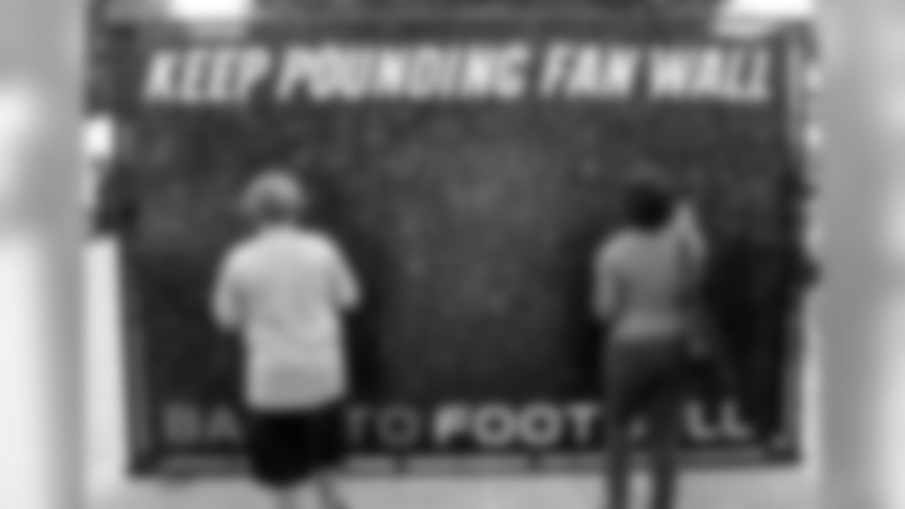 Fans sign the Keep Pounding Fan Wall.