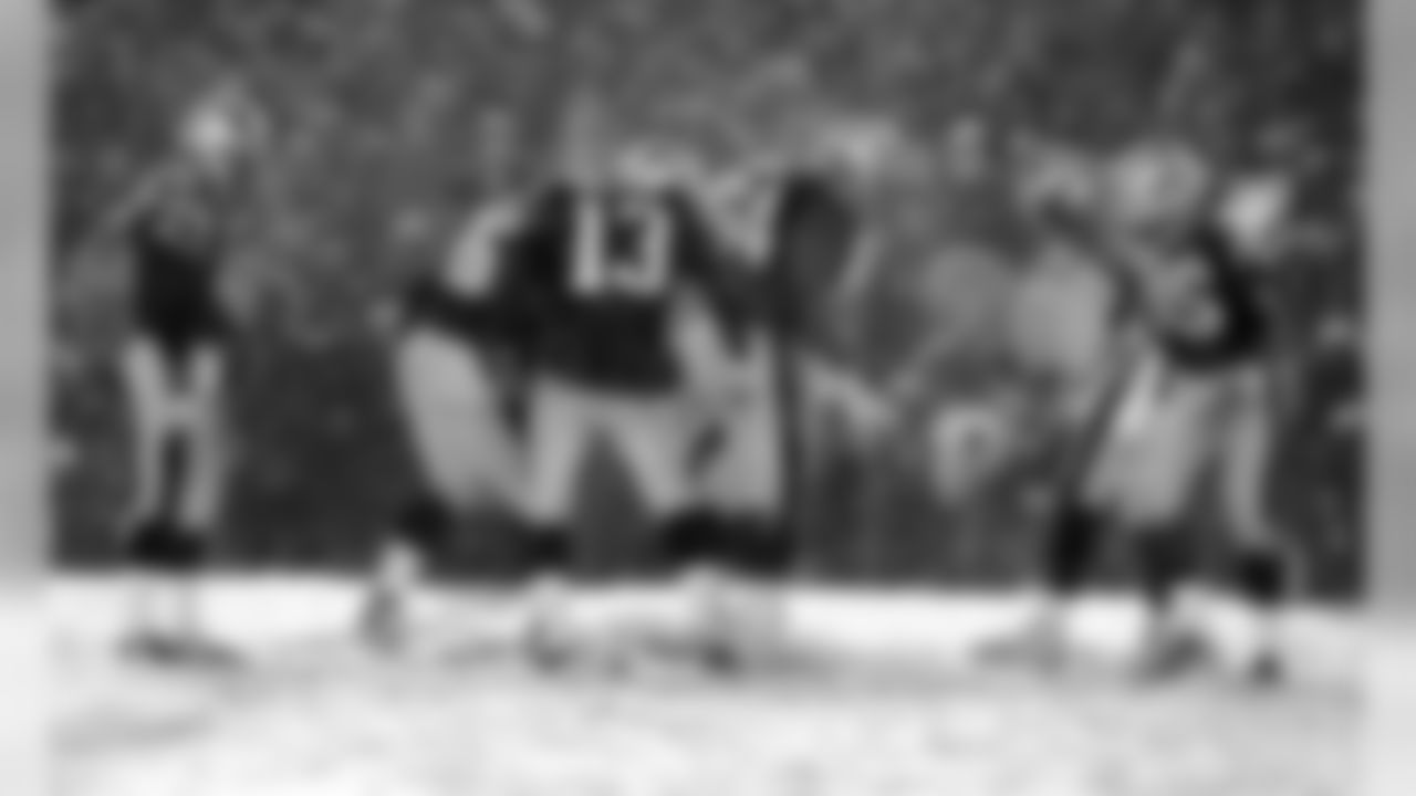 Patriots teammates clear the ground of snow with their feet, as they try to give Adam Vinatieri, far left, the best footing to kick the winning field goal in overtime. New England Patriots face the Oakland Raiders in an AFC playoff game at Foxboro Stadium in Foxborough, MA on Jan. 19, 2002.