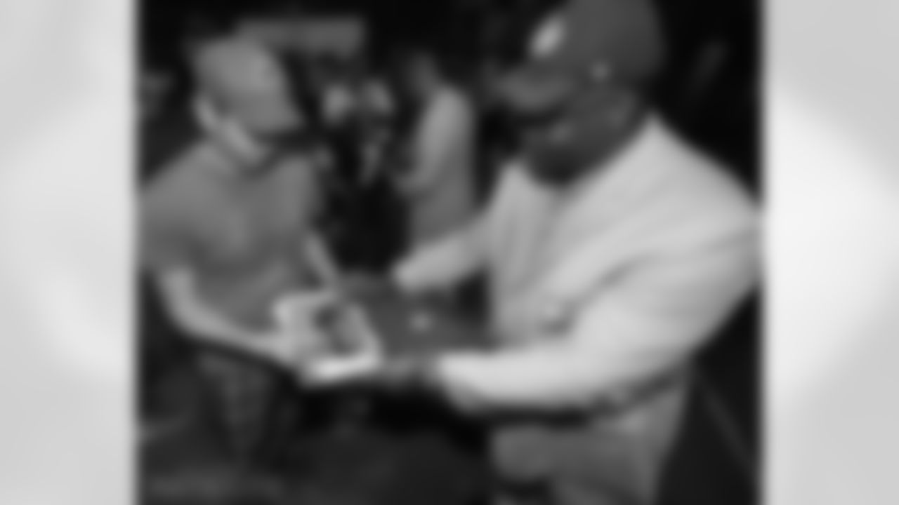 Andre Tippett signs a photo for a fan.