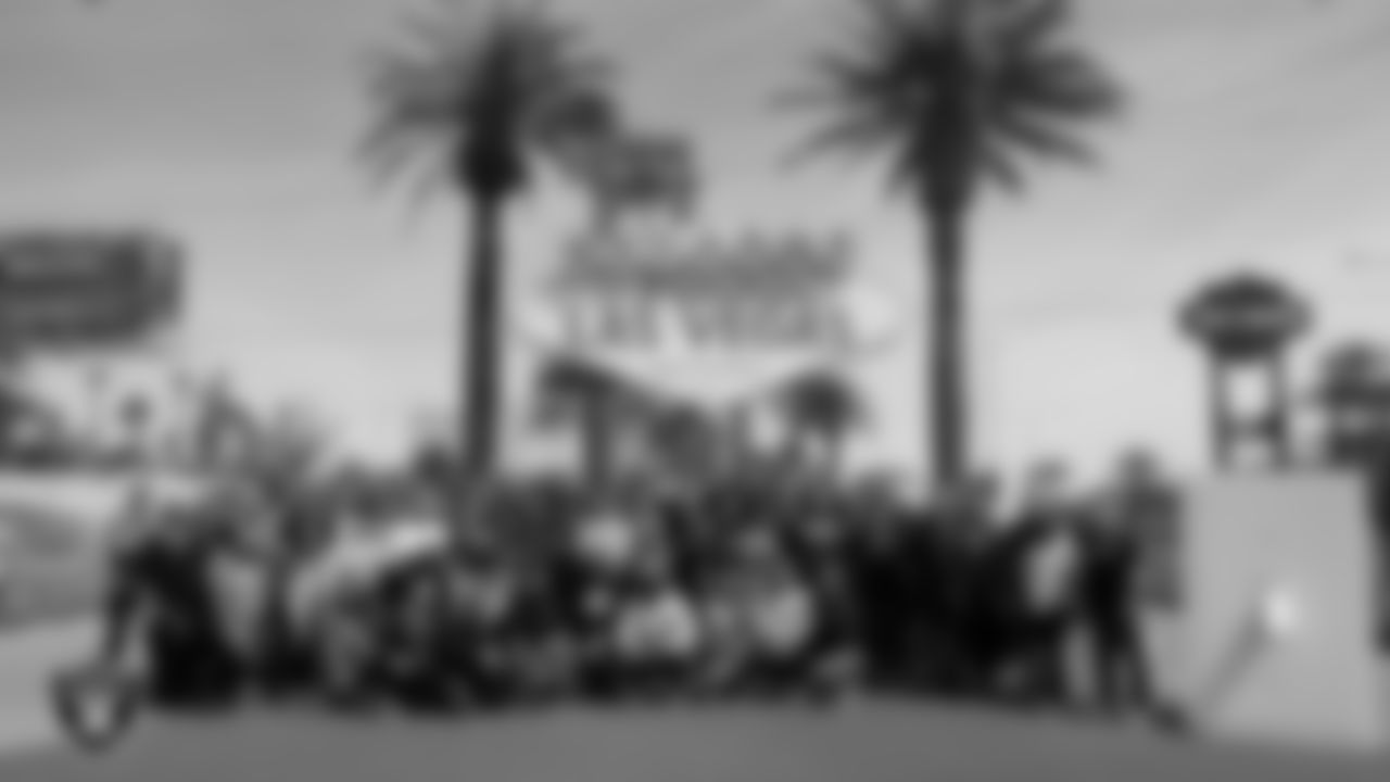 Members of the Las Vegas Raiders pose for a photo in front of the "Welcome to Fabulous Las Vegas" sign before it was lit up silver and black.