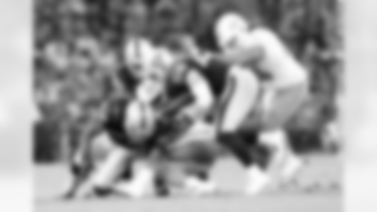 DL C.J. Wilson makes the tackle and gets help from LBs Khalil Mack and Miles Burris.