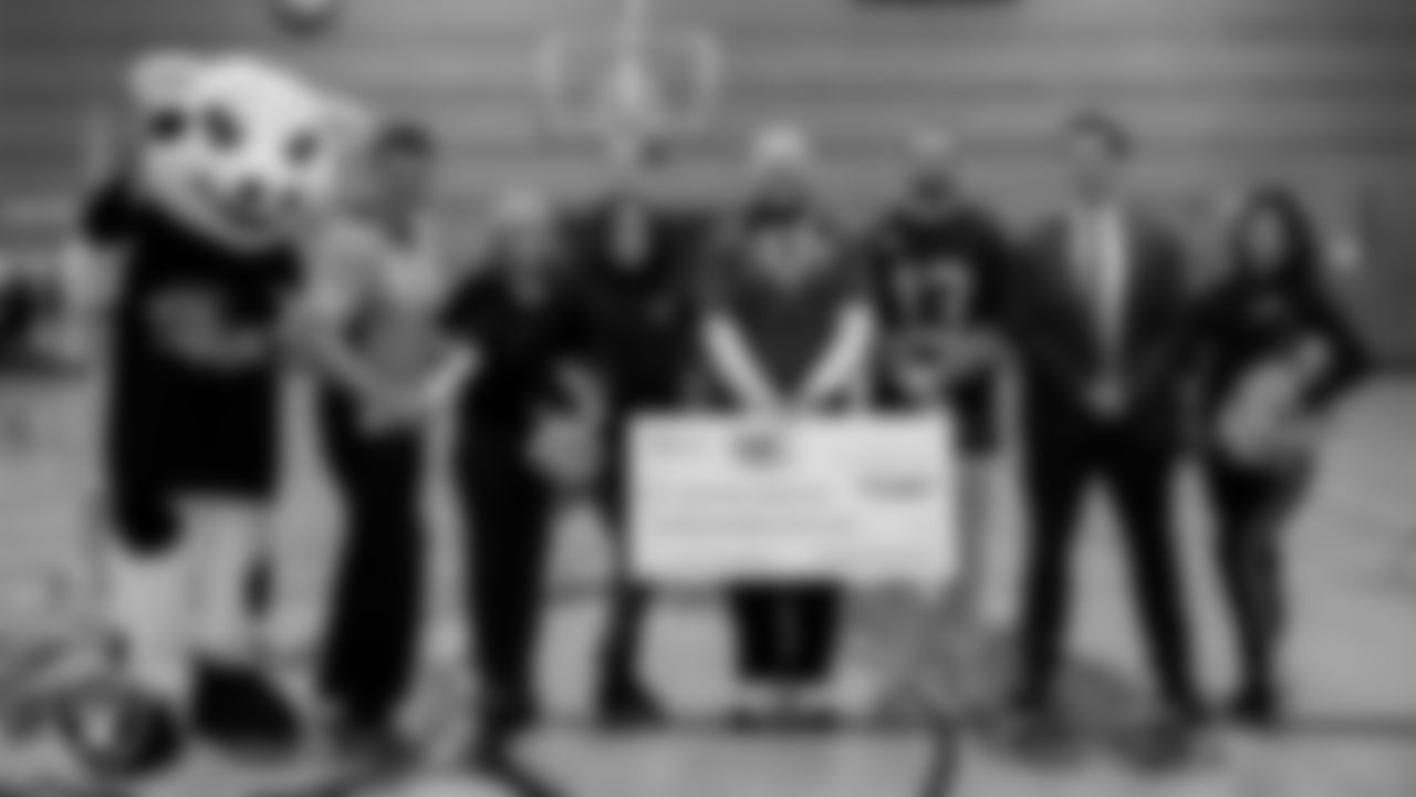 Daisy the mascot, nutrition manager Jack Yarberry and general manager Libby Lovig of the Dairy Council with Raiderettes Audrey and Katsura, Jerome Mack Middle School PE teacher Joseph Migoni, Las Vegas Raiders wide receiver Hunter Renfrow (13) and Raiders activation coordinator Austin Crafton during an assembly where the Raiders and Dairy Council awarded $10,000 to Jerome Mack Middle School as the 2022 "Hometown Grant" winner to continue efforts to bring healthy habits and new PE activities to students at Jerome Mack Middle School.