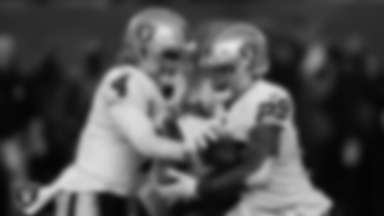Las Vegas Raiders quarterback Derek Carr (4) hands the ball off to running back Josh Jacobs (28) during the postseason away game against the Cincinnati Bengals.