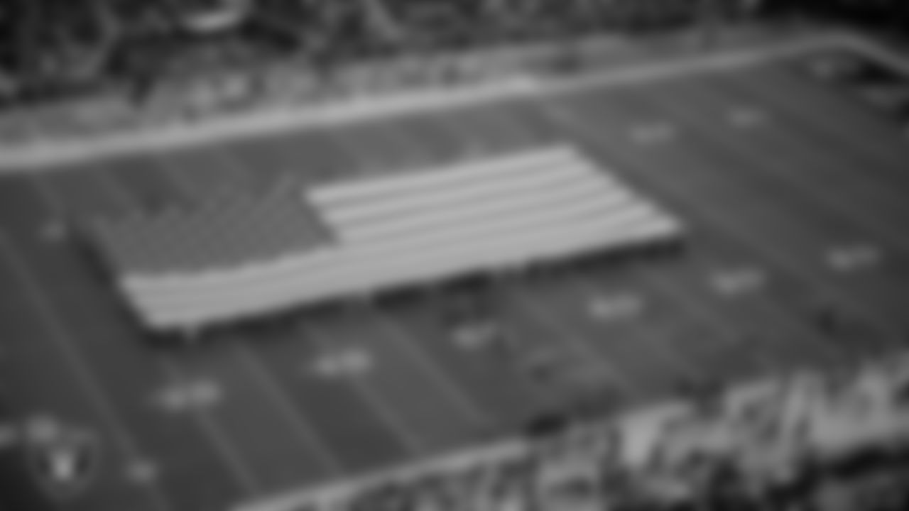 The American flag is displayed by Personal Seat License (PSL) holders on the field during the national anthem before the Las Vegas Raiders' preseason home game against the New England Patriots at Allegiant Stadium.