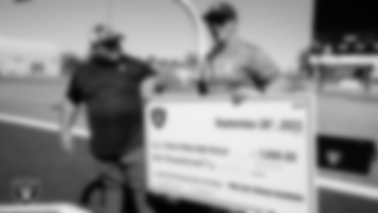 Las Vegas Raiders football development manager Jordan Aguilar presents Green Valley High School coach Clay Mauro with a check during the teams practice at Green Valley High School.