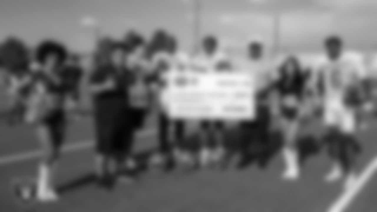 Raiderettes Vicky and Meghan and Las Vegas Raiders alumnus Roy Hart present Mojave High School's football coach Wes Pacheco with the Tom Flores High School Coach of the Week award.