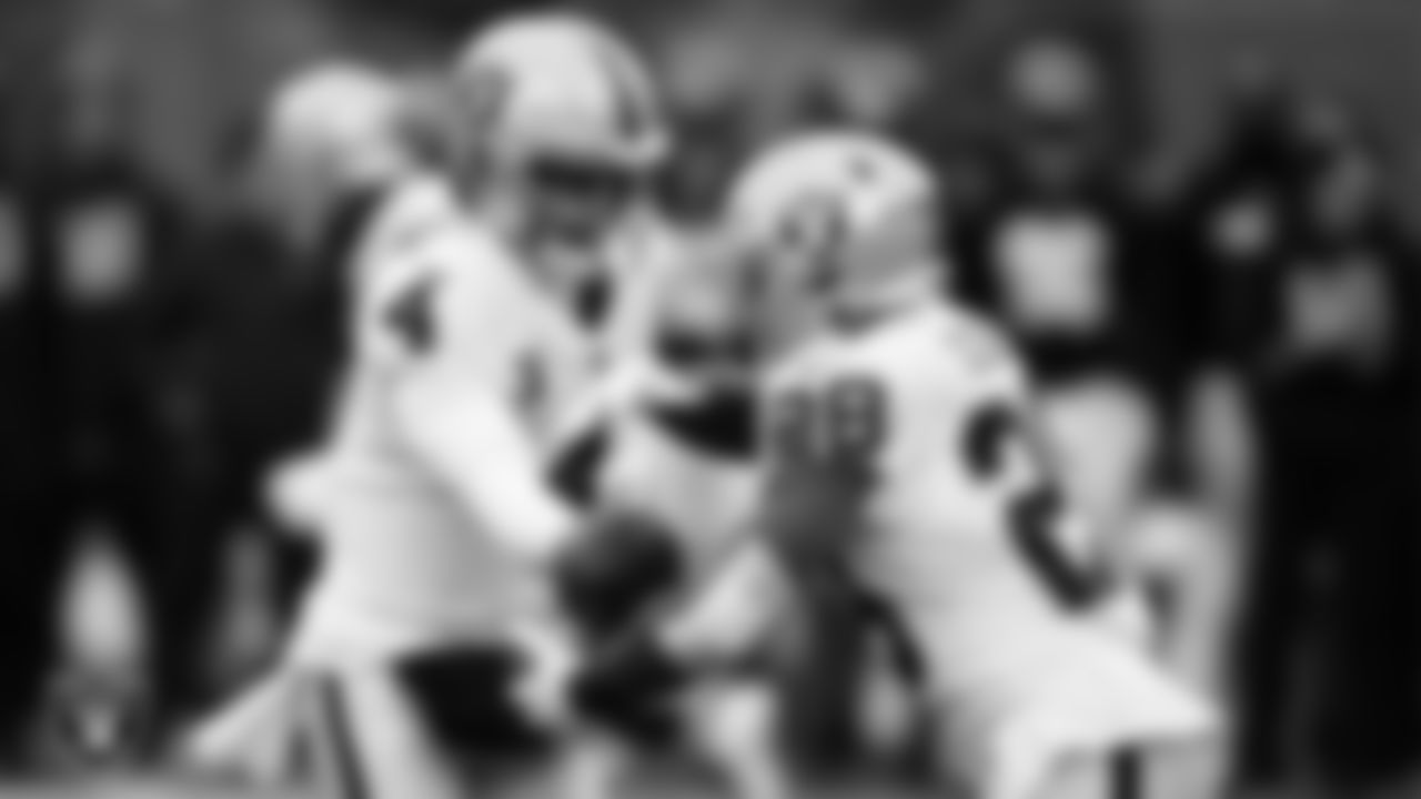 Las Vegas Raiders quarterback Derek Carr (4) hands the ball off to running back Josh Jacobs (28) during the postseason away game against the Cincinnati Bengals.