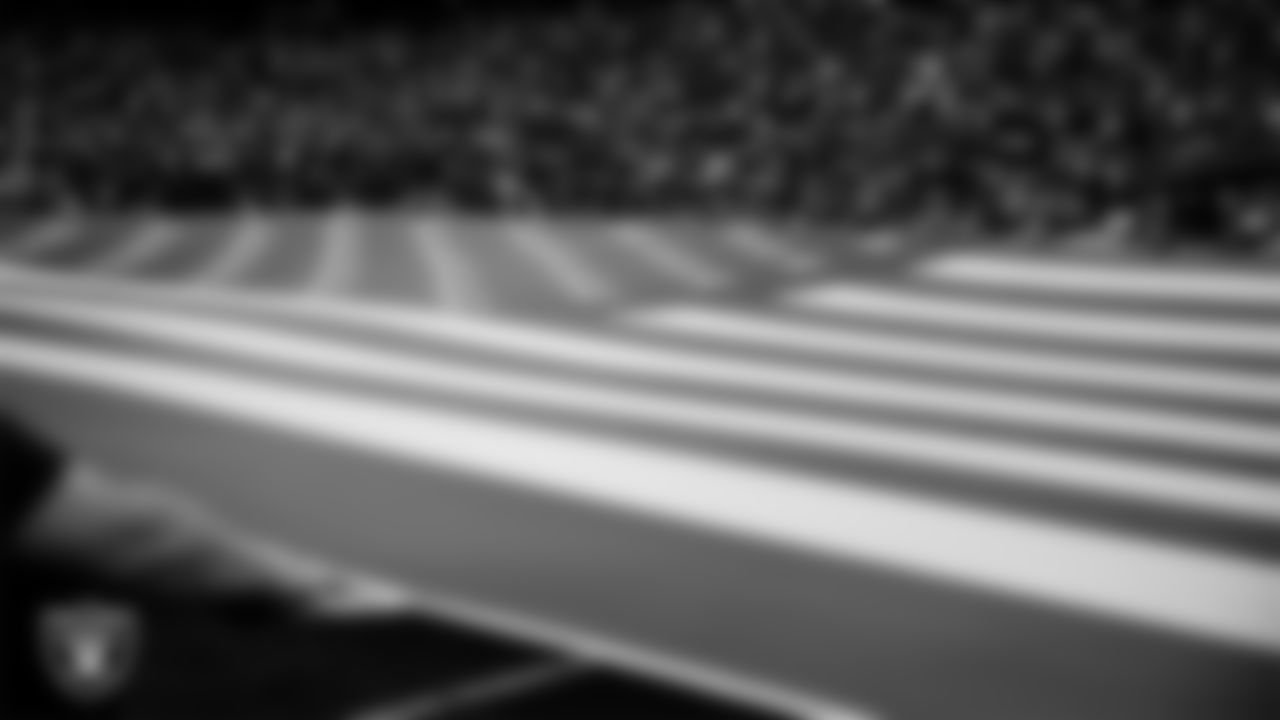 The American flag is displayed by members from the six military branches on the field before the Las Vegas Raiders regular season home game against the Indianapolis Colts at Allegiant Stadium.