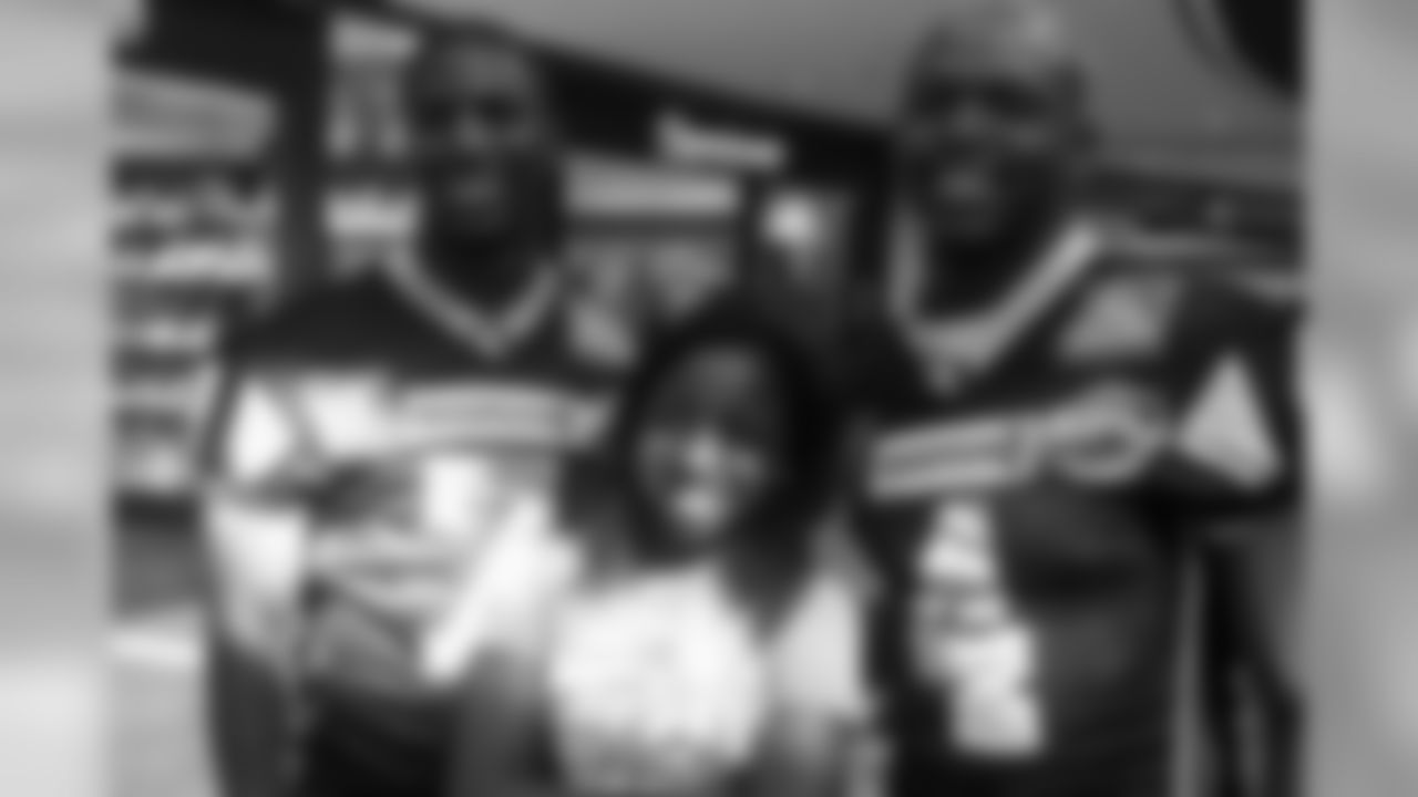 SWARCO Raiders players John Clements (7) and Talib Wise pose for a photo with a young fan at the DEZ Mall in Innsbruck, Austria. Photo by Jeanette Thompson.