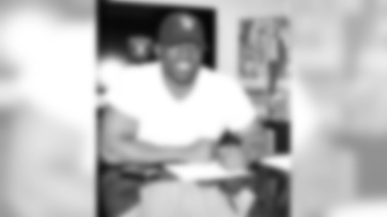 Justin Tuck rocks a Raiders ball cap as he signs his contract.