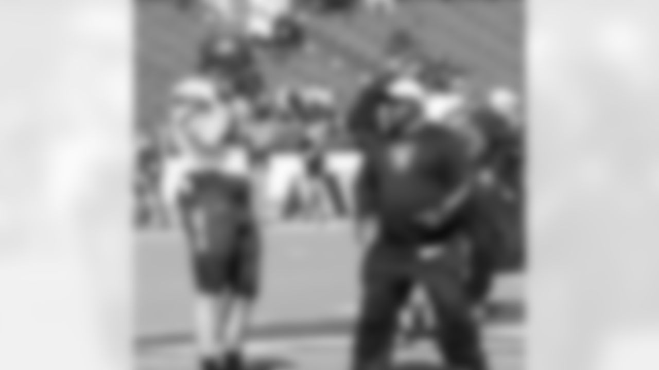 Running backs coach Kelly Skipper demonstrates technique to Harvard FB Kyle Juszcyzk.