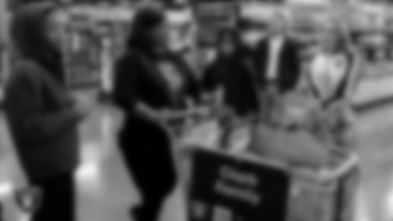 Raiderette Lilah goes around with a family as they pick out holiday food and gifts during Smith's Holiday Huddle.