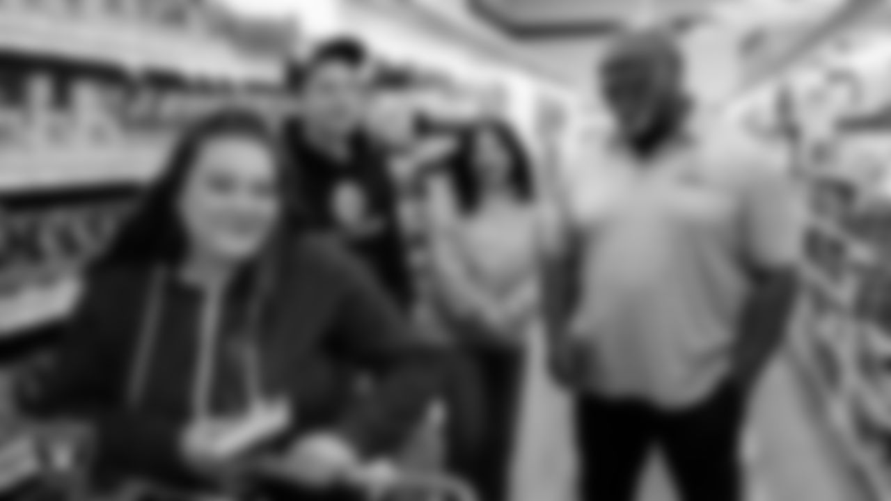 Las Vegas Raiders alumnus Roy Hart goes around with a family as they pick out holiday food and gifts during Smith's Holiday Huddle.