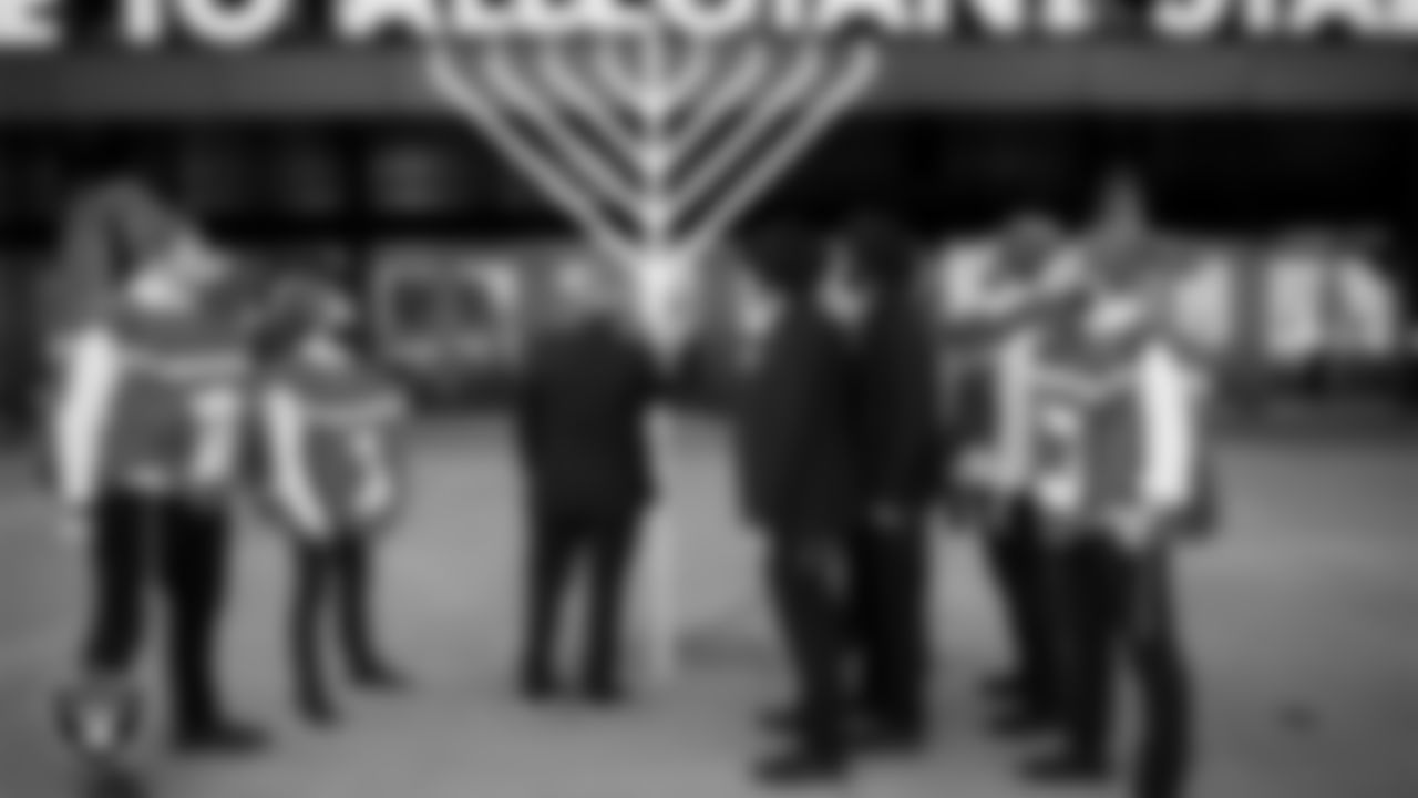 Rabbi Mendy Harlig of the Chabad of Southern Nevada, Rabbi Levi Harlig of the Chabad Friendship Circle and The Dancing Dreidels say a ceremonial prayer and light a menorah to celebrate the first day of Hanukkah before the Las Vegas Raiders regular season home game against the New England Patriots at Allegiant Stadium.