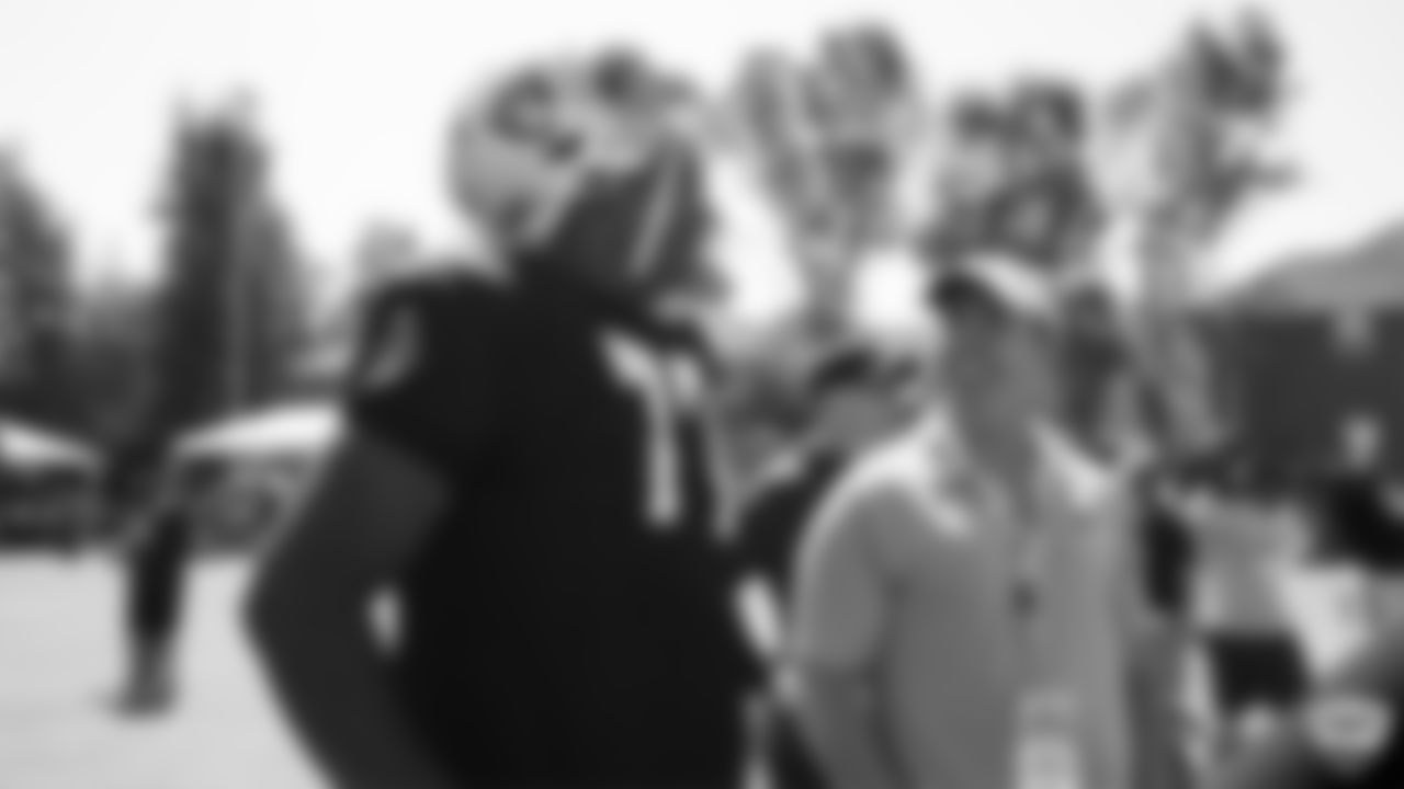 Raiders tackle Trent Brown (77) and alumnus Bill Romanowski on the field for a joint practice with the Los Angeles Rams at 2019 Training Camp.