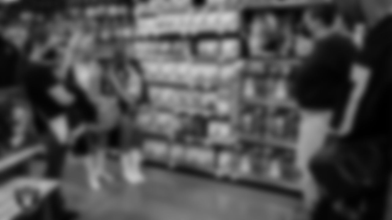 Raiderettes Melody and Katsura go around with a family as they pick out holiday food and gifts during Smith's Holiday Huddle at Smith's Marketplace.
