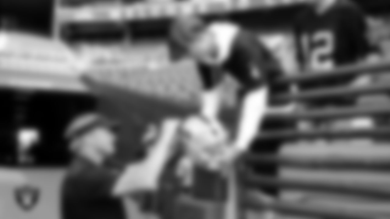 Raiders Head Coach Jon Gruden signs an autograph before a game in 2018.