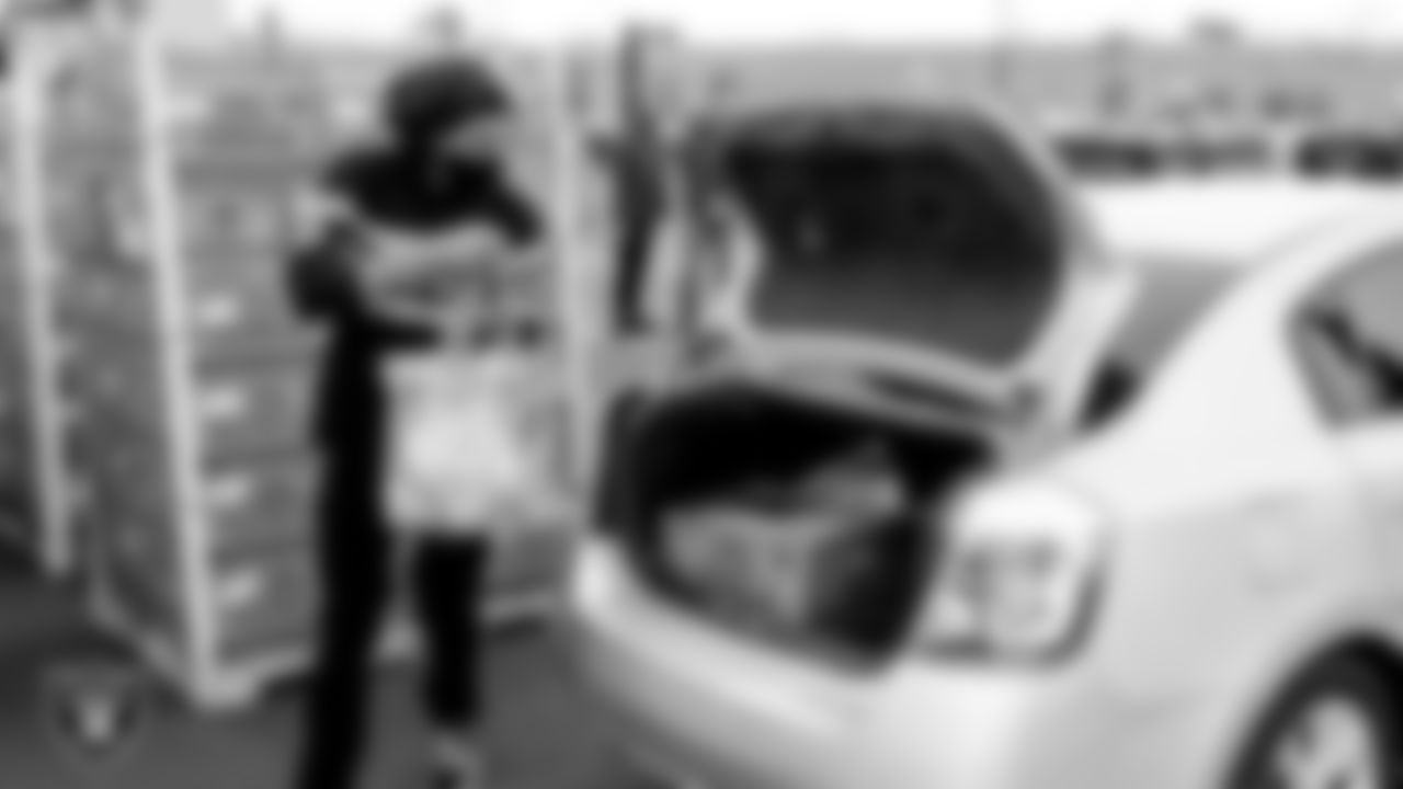 A Three Square Food Bank worker loads food for a Thanksgiving dinner into a car at Allegiant Stadium.