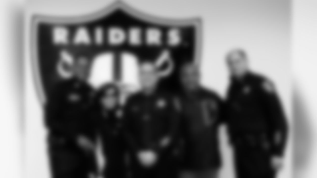 The Oakland police officers pose for a photo with Raiders Chief Executive Amy Trask and Head Coach Hue Jackson. Photo by Tony Gonzales.