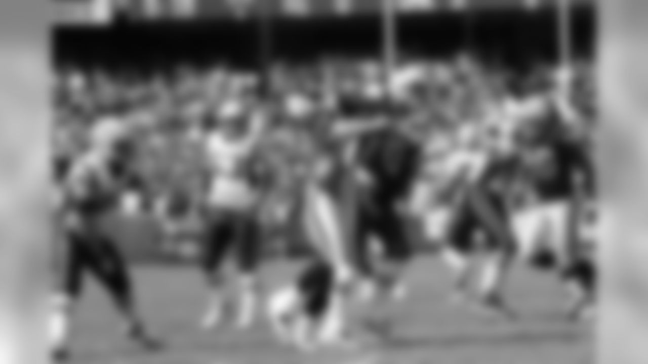 QB Tom Brady gets wrapped up by the Raiders defender.